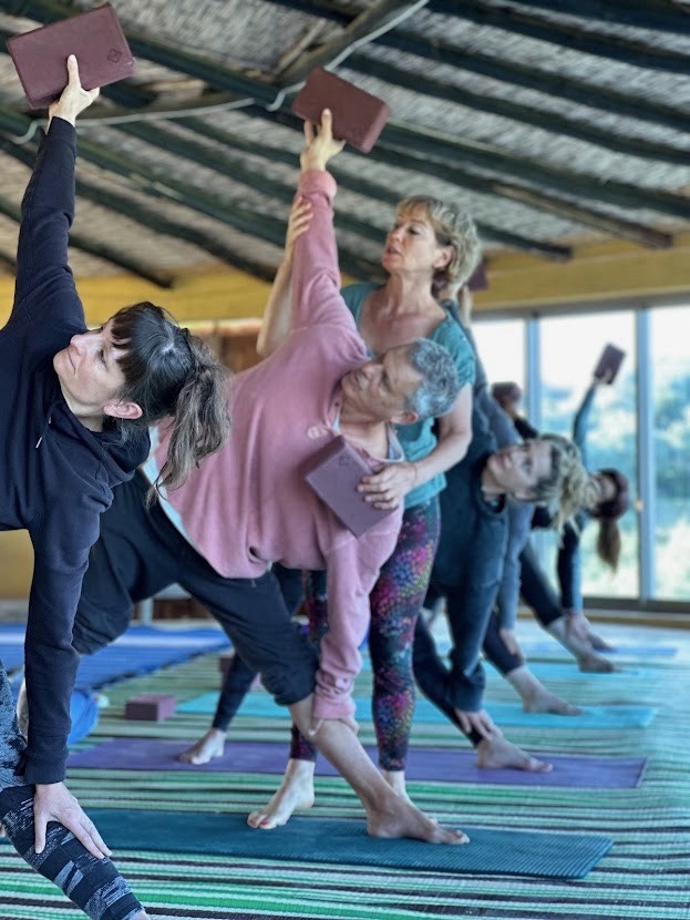 Cours de yoga avec Naura et des élèves utilisant des briques