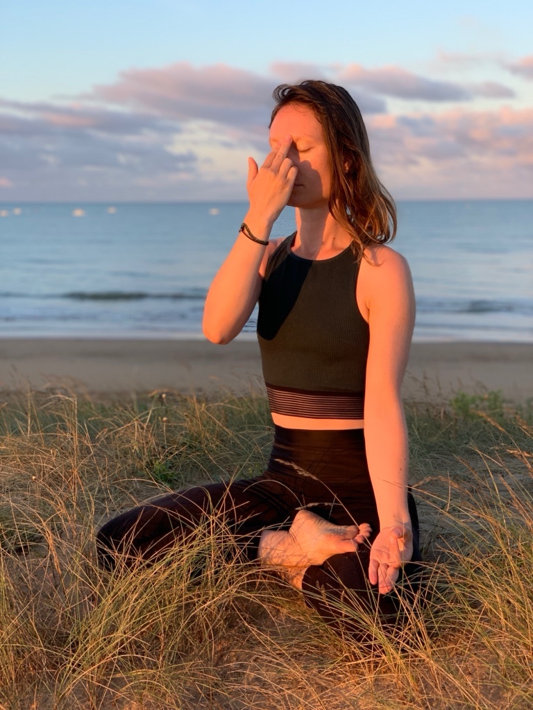 Lucie pratiquant un exercice de respiration assise face à la mer